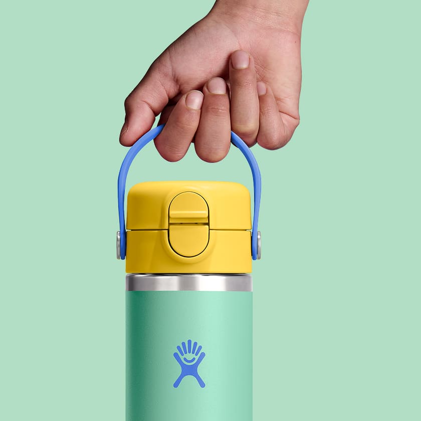 Hydro Flask Kids 18 oz Wide Mouth Bottle With Covered Straw Cap And Boot – Easy to carry – child holding bottle by the carry strap