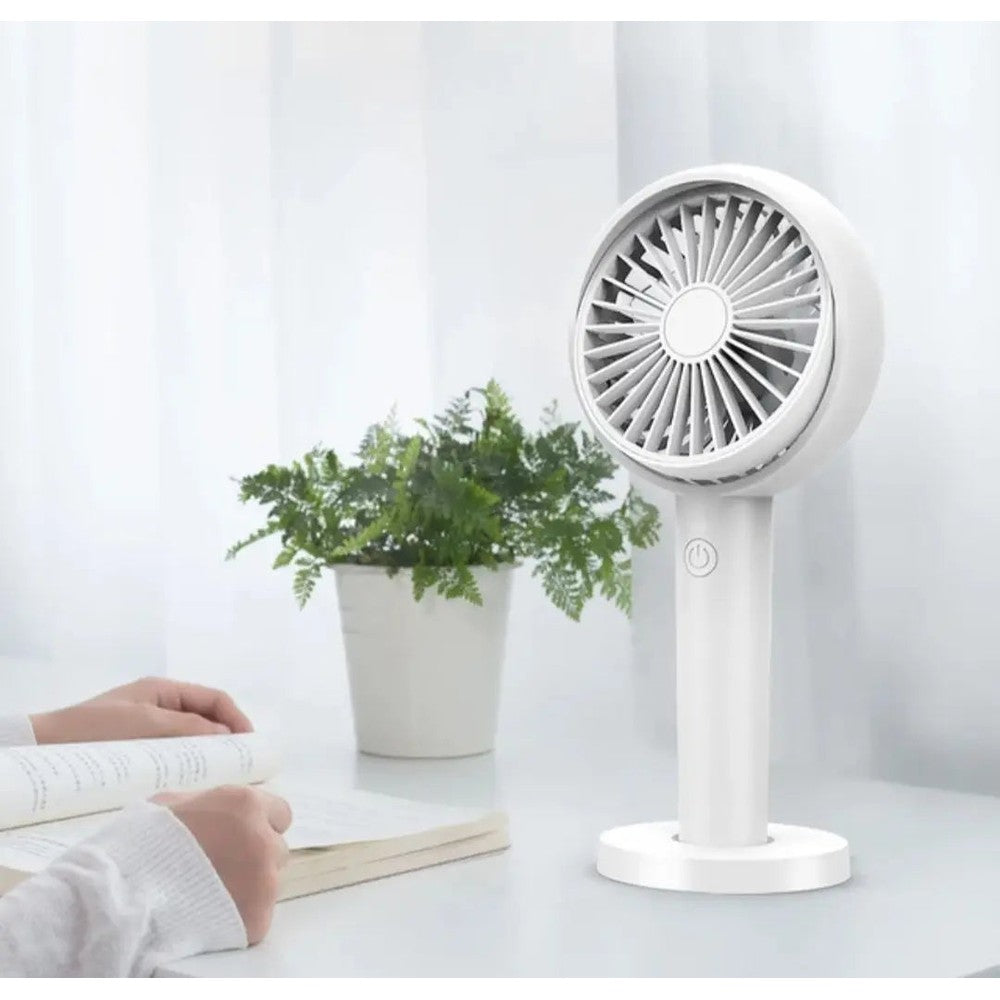 I2 Handheld 3-Speed Lithium Battery Fan in white on a desk beside a plant and book, demonstrating portable cooling.