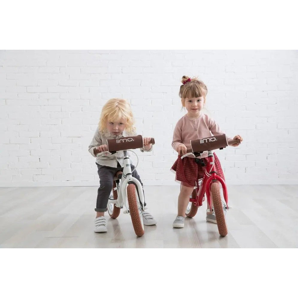 Iimo Balance Bike for kids, white and red frames with brown handlebar pads, two children ride indoors.
