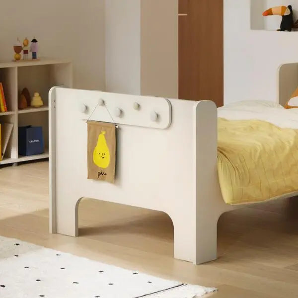Iloom Cabin Hanging Hanger on a white toddler bed; four hooks hold a yellow pear-tagged note.
