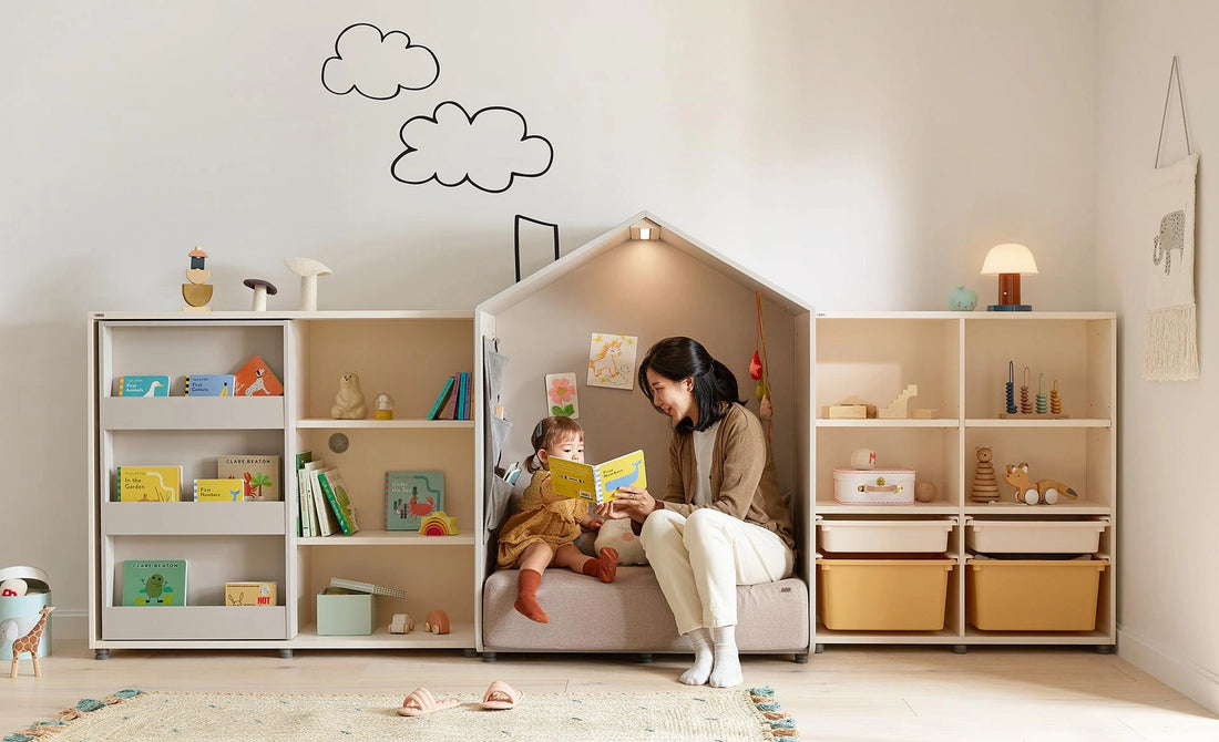 Complete manufacturer room photograph of an adult and child reading in the grey Eddi sofa-style reading house; adjacent furniture is separate.