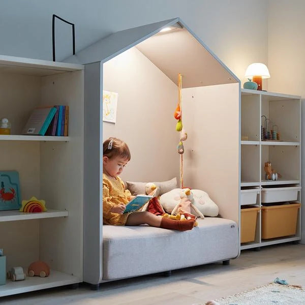 Original distinct side-angle room photograph of a child reading in the grey Eddi reading-house sofa.
