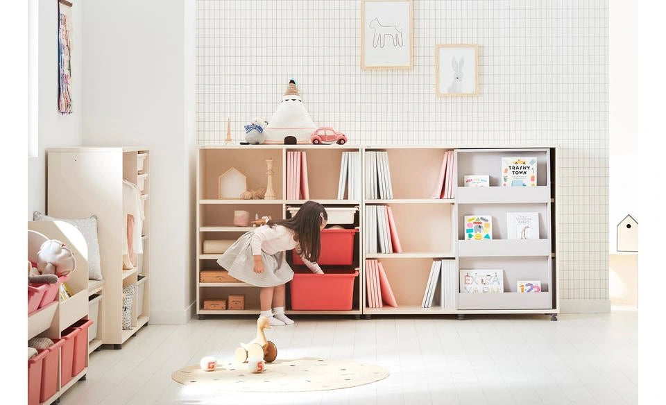 Whole room photograph with the sliding bookshelf next to separate toy storage and a child; no age is inferred.