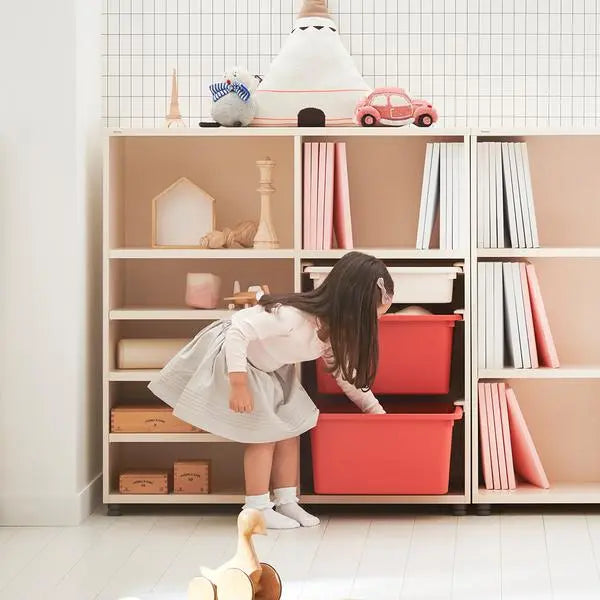Iloom Eddi Kids Bookshelf With Toy Storage in beige; child places toys into bright red bins.