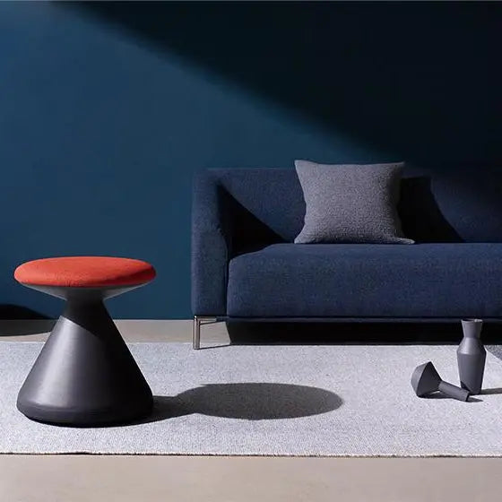 Iloom Fungus Chair in a blue living room, red cushion atop a black tapered base, modern compact seating.