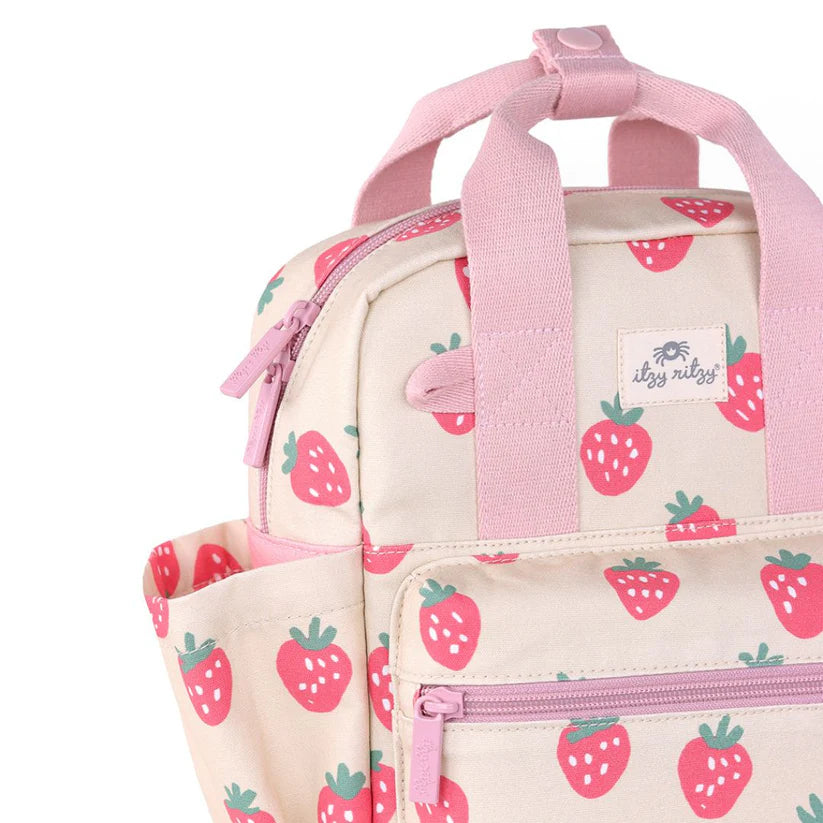 Itzy Ritzy Backpack strawberry-print cream canvas with pink straps, zippers, and front pocket.