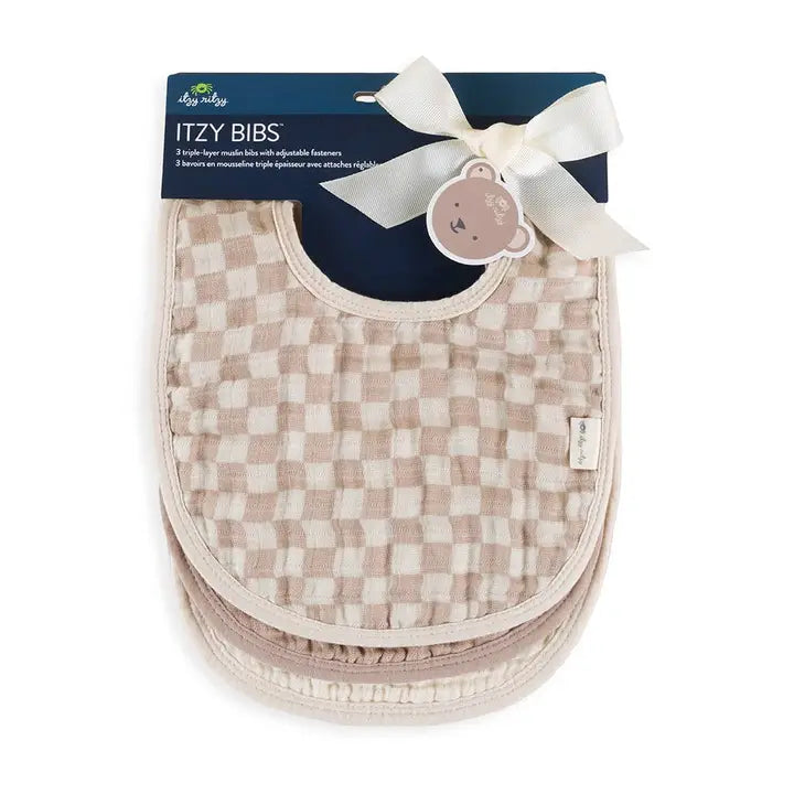 Itzy Ritzy Itzy Bibs baby bib in beige checkered muslin with cream trim and bow, packaged for mealtime.
