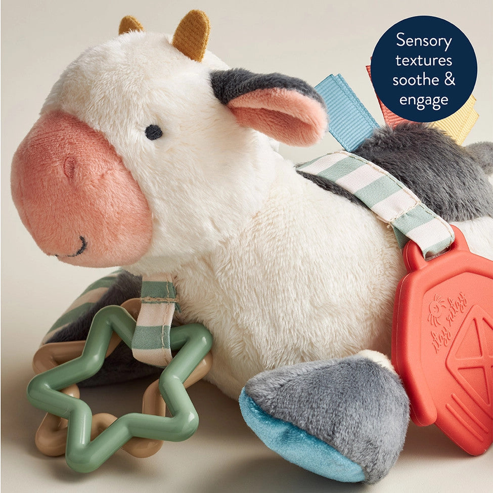 Itzy Ritzy Itzy Friends Link & Love Activity Plush cow with pastel straps and teether links