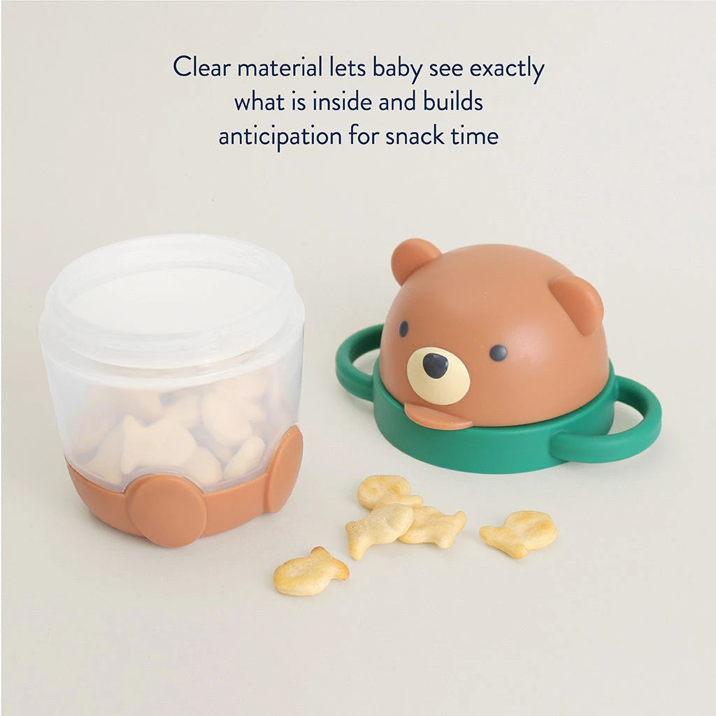 Itzy Ritzy Itzy Snack Pal Bear cup with snacks visible through clear sides and the character lid beside it.