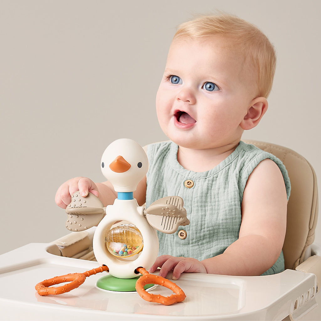 Baby playing with Itzy Twist & Bop Gracie the Goose on a high-chair tray