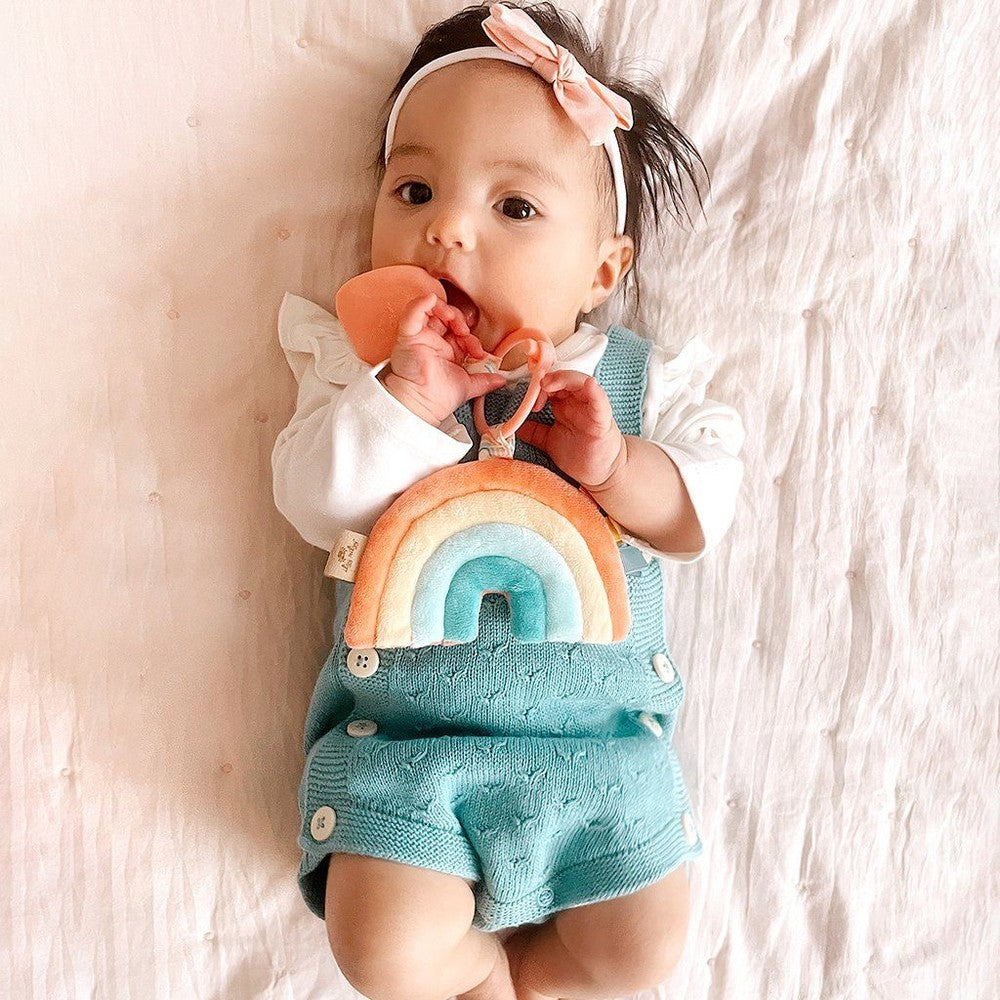 Itzy Ritzy Pal plush teether rainbow arc with baby in teal romper and pink headband