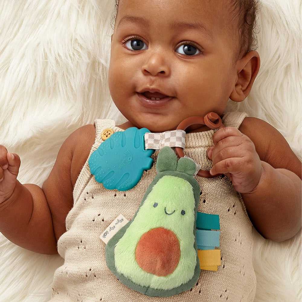 Itzy Ritzy Pal Plush and Teether avocado plush teether with brown ring and colorful tabs for babies