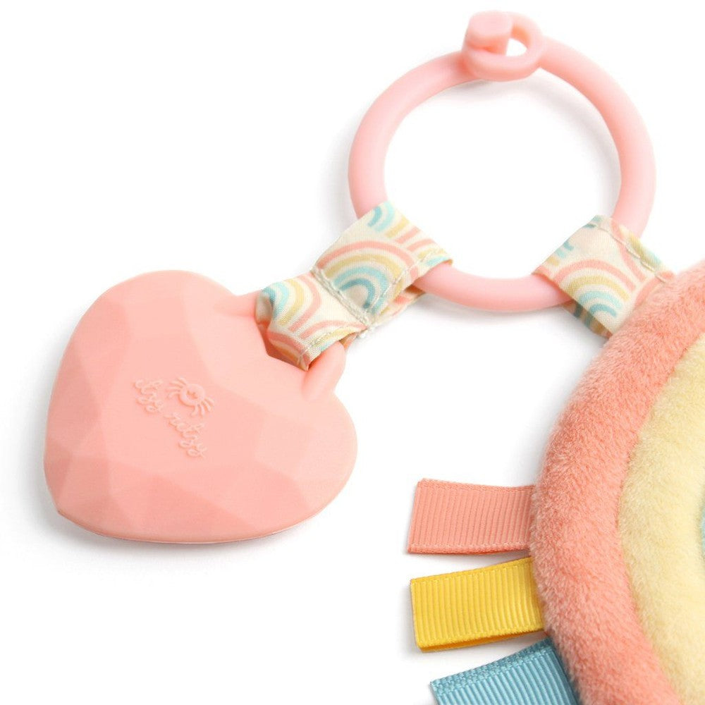 Itzy Ritzy Pal plush and teether; pink heart silicone teether attached to ring with rainbow ribbon bow