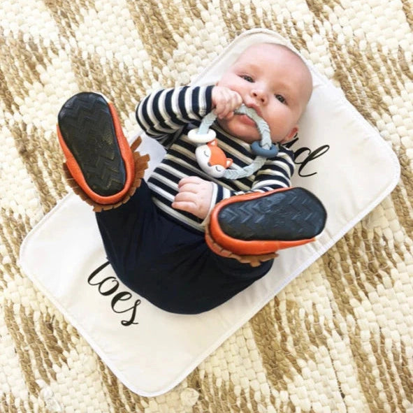Itzy Ritzy Rattle Silicone Teether with blue-gray ring for baby, infant on cream mat