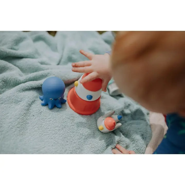 Itzy Ritzy Stack & Squirt bath toy set; blue octopus and red stackable cup being stacked and squeezed by a child.
