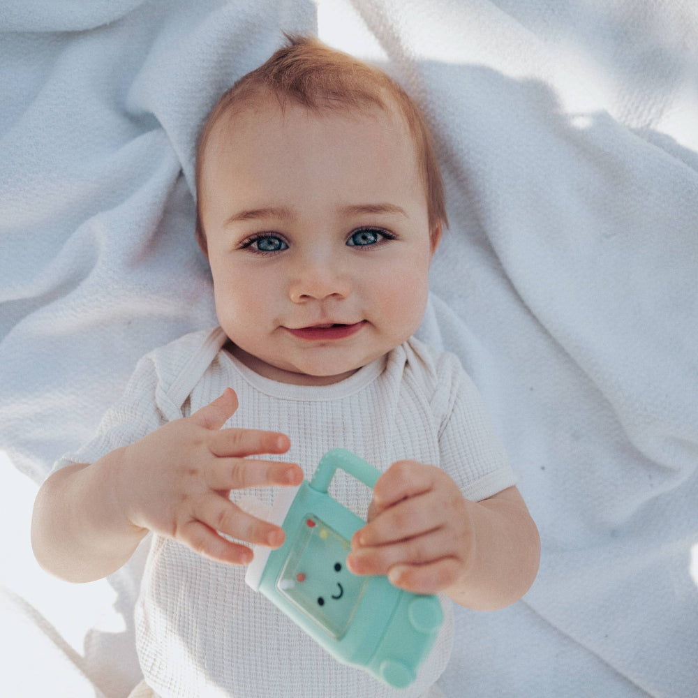 Itzy Ritzy Sweetie Shake Plus teether rattle in teal mint with a smiley face for babies