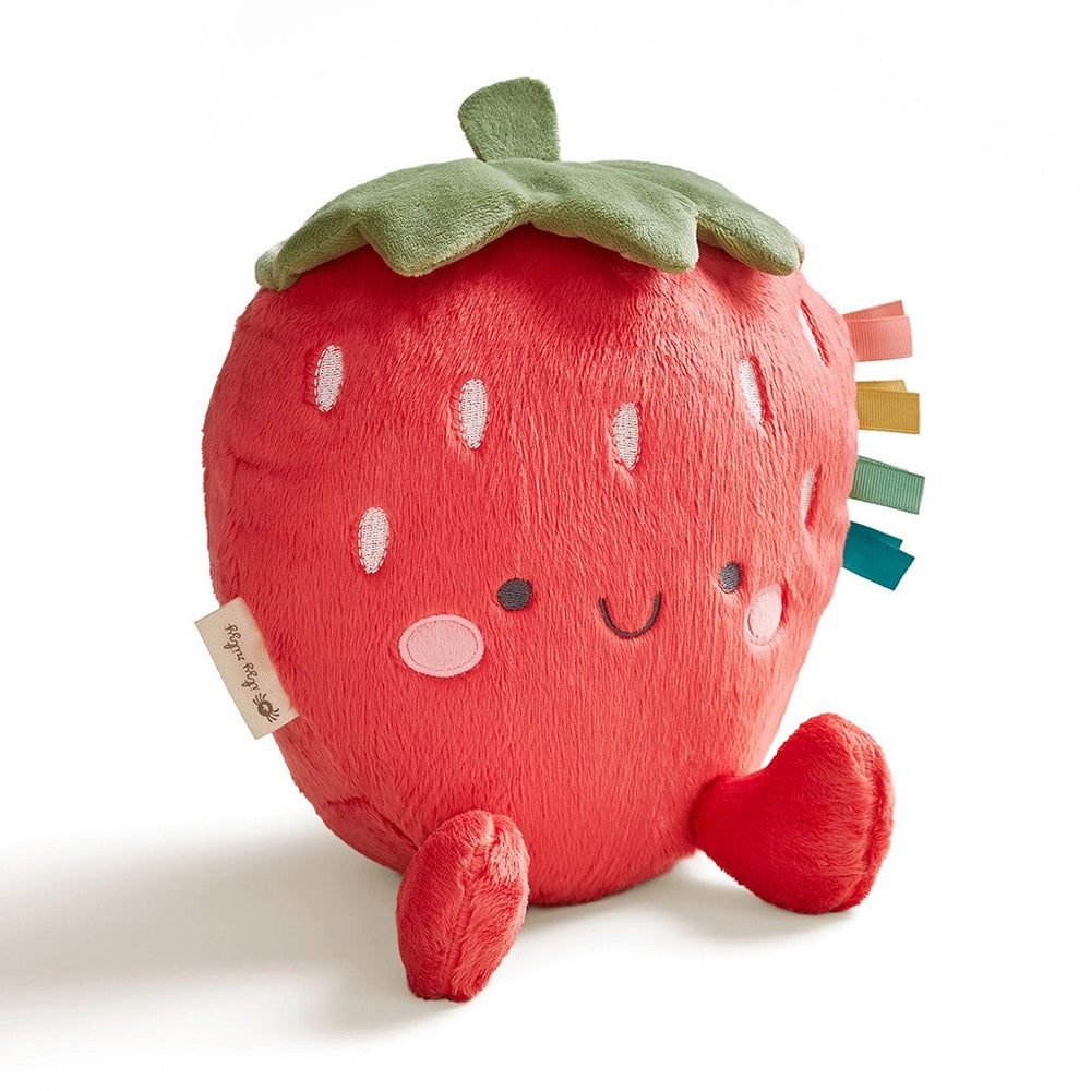 Itzy Ritzy Sweetie Snuggles Plush strawberry toy sits upright with rainbow ribbon tabs and a green leaf.