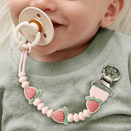 Itzy Ritzy Sweetie Strap Plus pacifier clip in pink with strawberry bead accents for babies