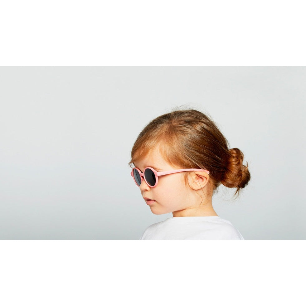 IZIPIZI Kids pastel pink round sunglasses worn by a toddler girl with a bun