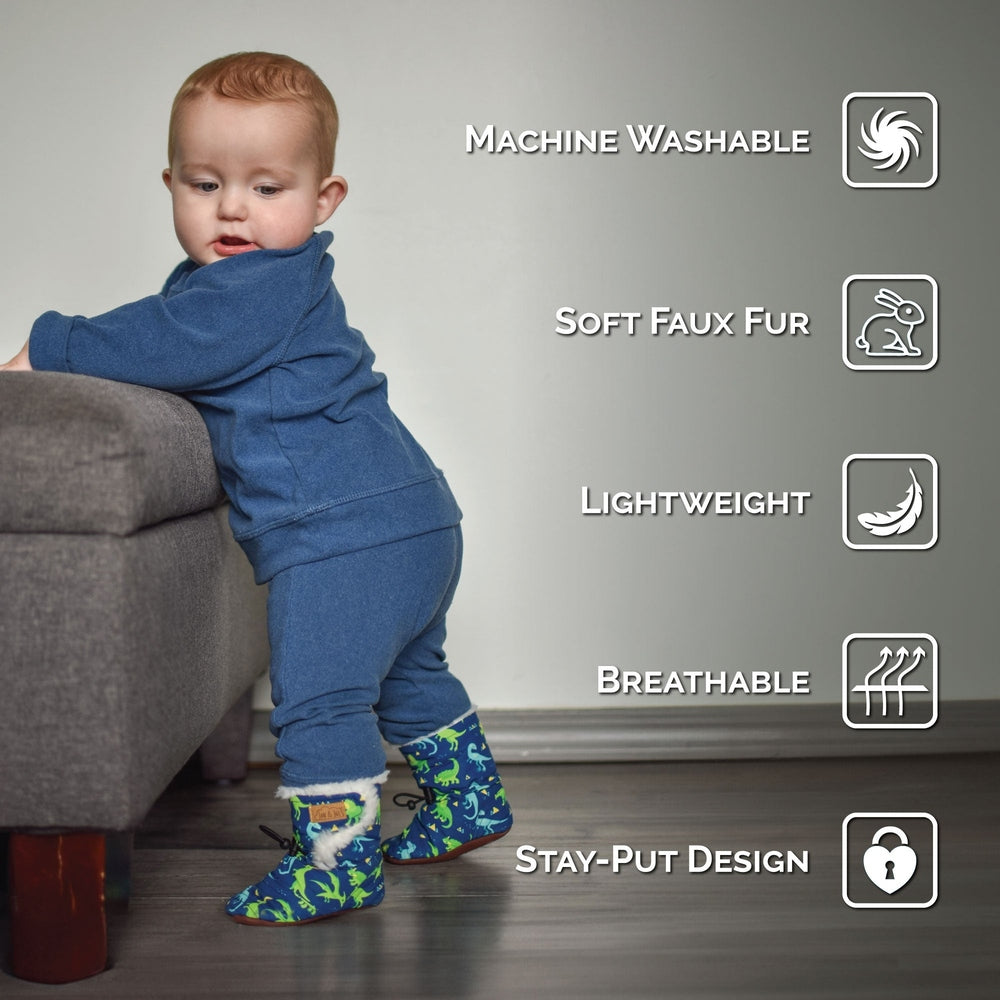 JAN & JUL Baby Stay-Put Winter Booties Space Dinos, blue with soft faux fur, as baby stands on a sofa.