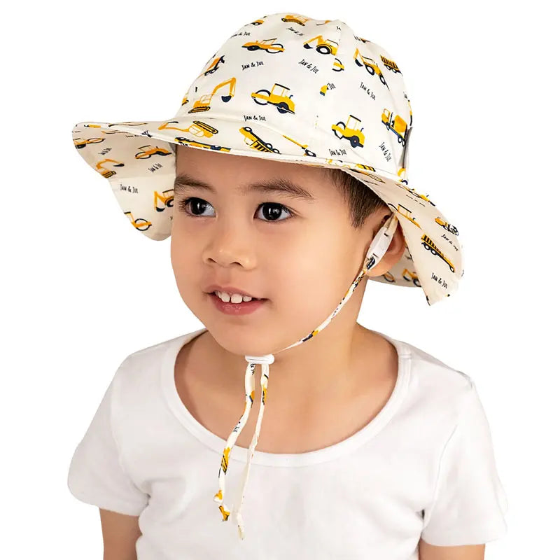 Jan & Jul Cotton Adventure Hats Little Diggers toddler bucket hat with yellow construction vehicle print; chin strap tied under chin.