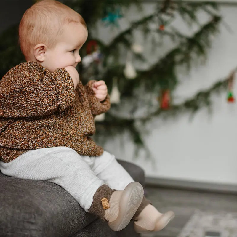 Jan & Jul Cozy Sock Shoes Oat for babies in beige knit with soft soles, worn on a baby's feet.