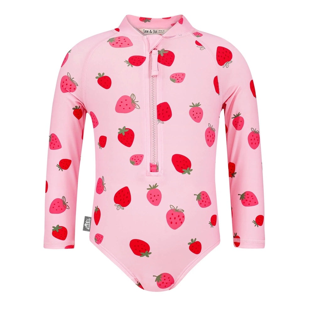 Jan & Jul Girls One Piece UV Swimsuit Pink Strawberry worn by child while she zips the front zipper.