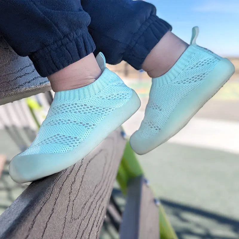 JAN & JUL Jelly Jumper Flow Shoes Mint toddler sneakers worn by a child on a railing, knit sock-style upper.