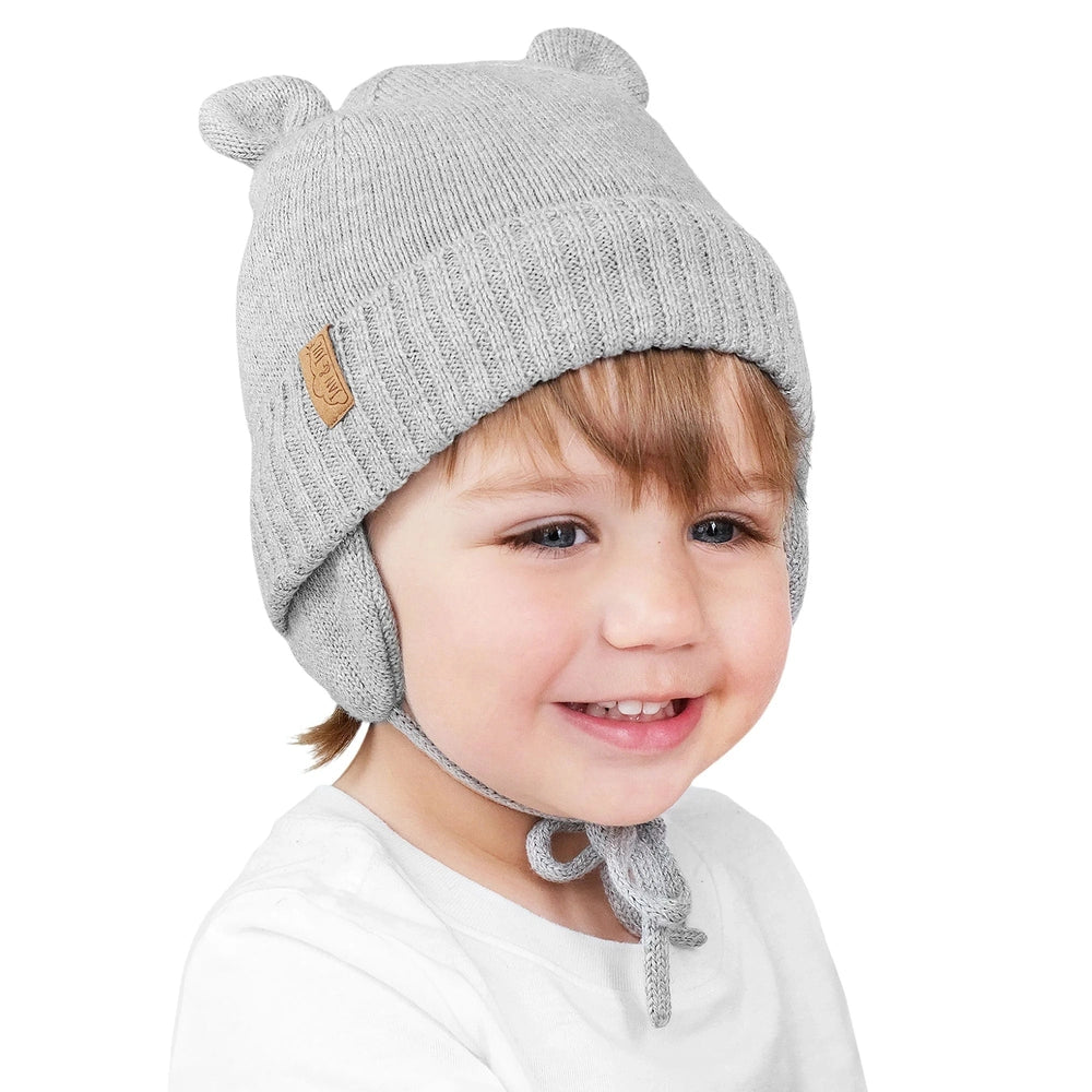 Jan & Jul Kids Bear Knit Hats Soft Grey on a smiling toddler; knit beanie with bear ears, ear flaps and chin strings.