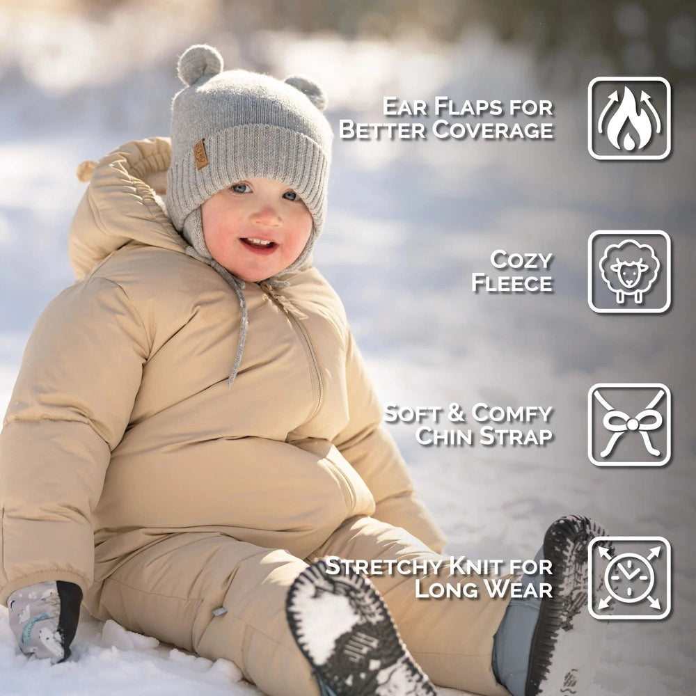 JAN & JUL Kids Bear Knit Hat in Soft Grey worn by a toddler in a warm snowsuit, showing ear flaps for coverage.