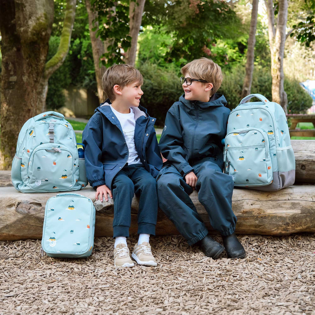 Kids with matching Home Sweet Home lunch bags and backpacks outdoors