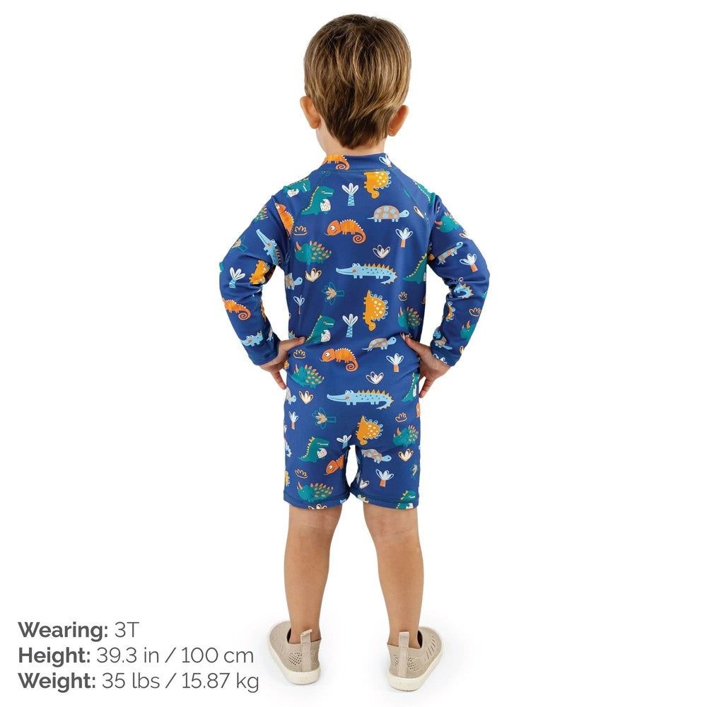 JAN & JUL Kids One Piece UV Sun Suit Dino Buddies, back view of a child standing with hands on hips in blue dinosaur print.