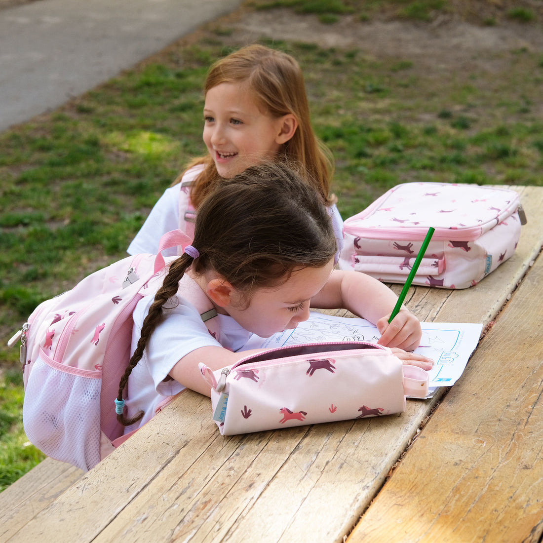 Kids drawing outdoors with the Pink Ponies pencil case and matching bags