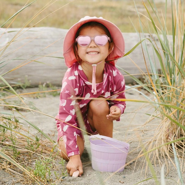Jan & Jul kids polarized heart sunglasses Frosty Lavender with pink frames worn by smiling girl