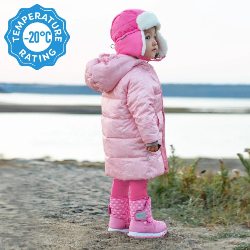 Jan & Jul Kids Tall Puffy Winter Boots Dusty Pink, Velcro strap fastened as a toddler stands on sandy beach by water.