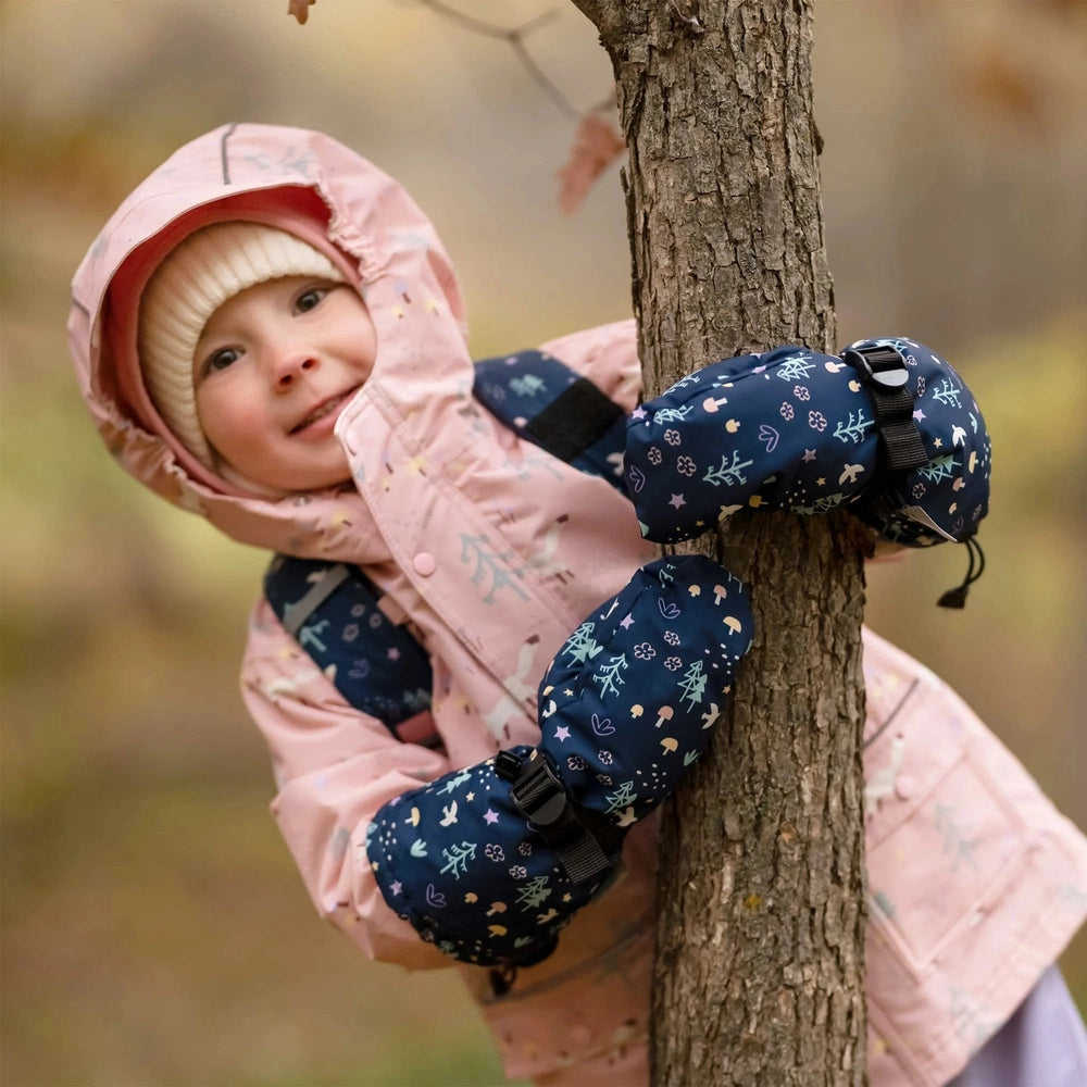 JAN & JUL Kids Waterproof Mittens Navy Forest; navy forest-print mittens strapped to a tree as a child hugs it