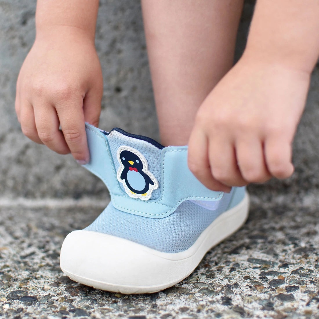 Jan & Jul Mini-Flyer Toddler Sneakers Penguin Party — child adjusting the hook-and-loop fastening tabs