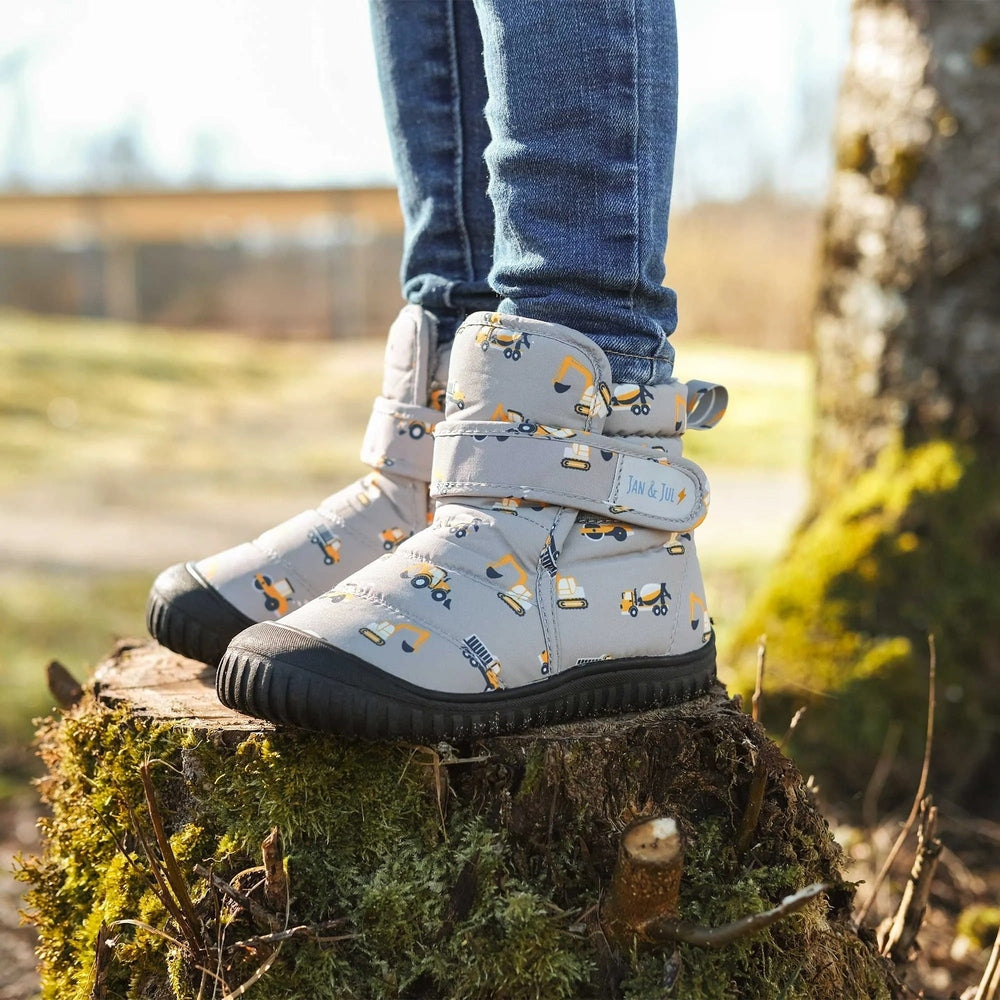 JAN & JUL Toasty Dry Booties Grey Construction; toddler boots with construction print and Velcro straps worn outdoors.