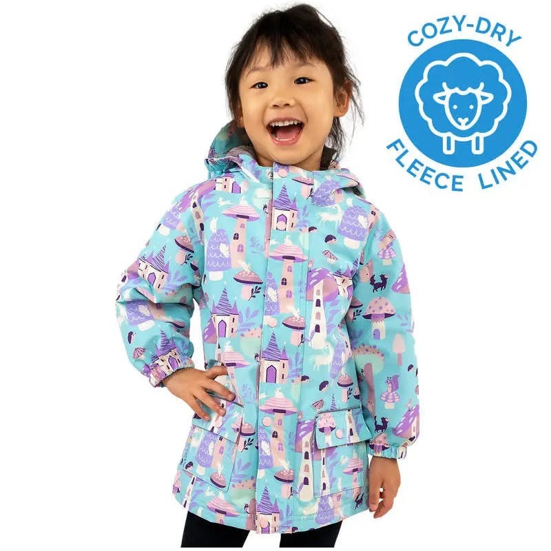JAN & JUL Enchanted waterproof rain jacket in turquoise castle print, fleece-lined, worn by a smiling kid.