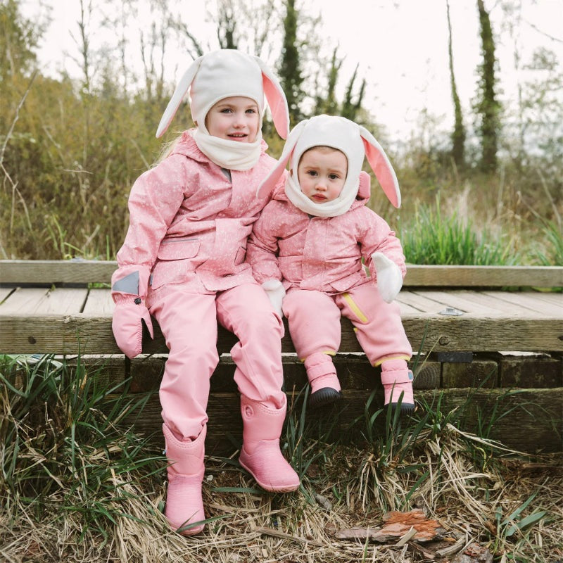 Jan & Jul Waterproof Puddle Dry Rain Jacket Prairie Flowers; two kids in pink coats sit on a bench outdoors, showing rain-ready jackets.