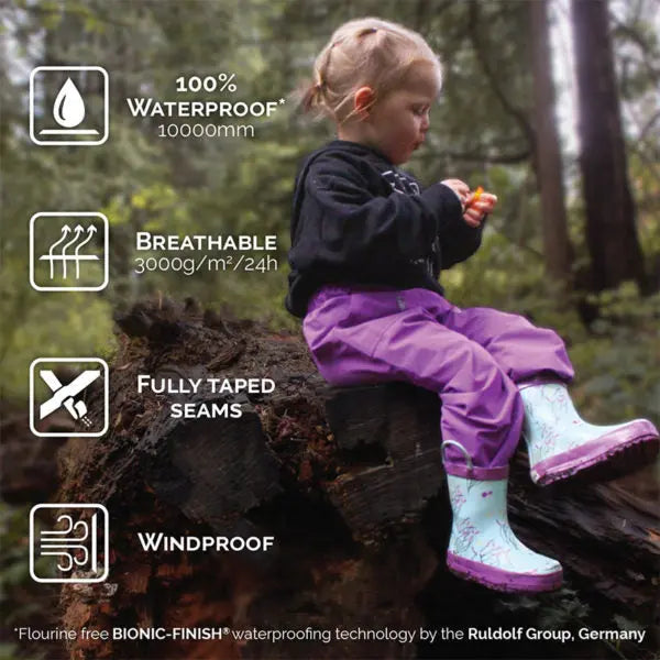 JAN & JUL Dreamscape Waterproof Puddle Dry Rain Pants for kids in purple; child sits on a log, showcasing breathable, fully taped seams.