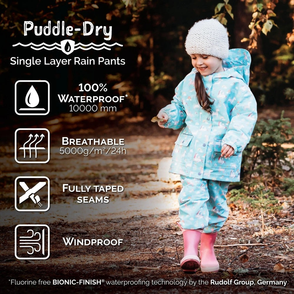 Jan & Jul Waterproof Puddle-Dry rain pants Greystone, child walks a rainy path showing fully taped seams.