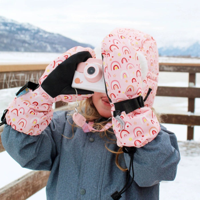 JAN & JUL Waterproof Toasty Dry Mitten Pink Rainbow for toddlers; child on a snowy dock photographs with a pink camera.