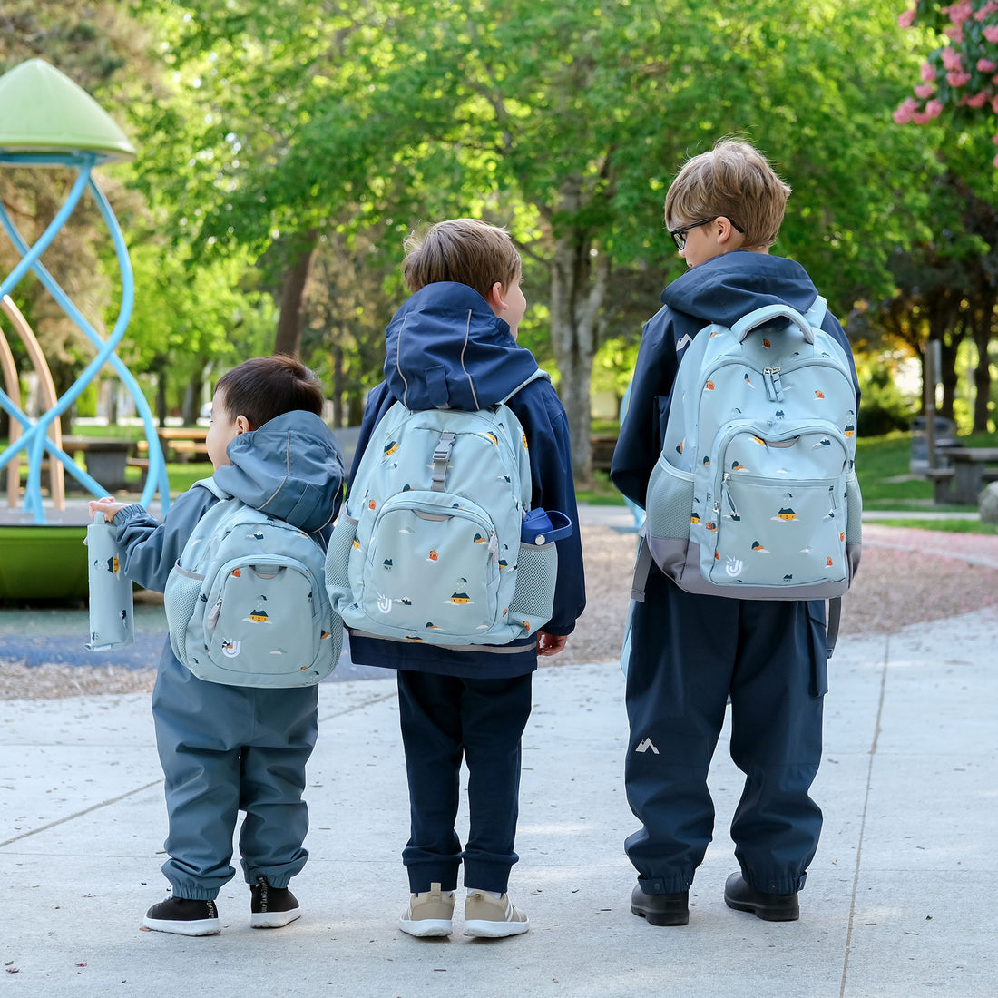 Kids wearing Jan & Jul Home Sweet Home backpacks at the playground
