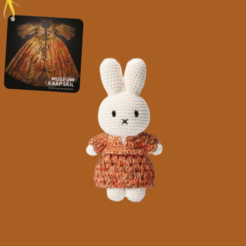 Just Dutch Miffy handmade plush bunny in an orange knitted dress, standing upright with a Museum Kaap Skill tag.