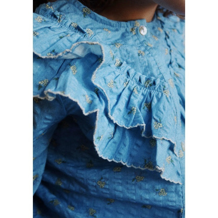 Konges Slojd Kim Frill Blouse Billie Blue, blue cotton top with frill trim and tiny floral print worn by a child