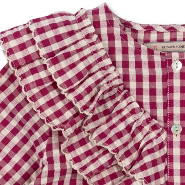 Konges Slojd Kim Frill Blouse Sangria Butter Check in pink-and-white gingham with layered ruffles at shoulder.