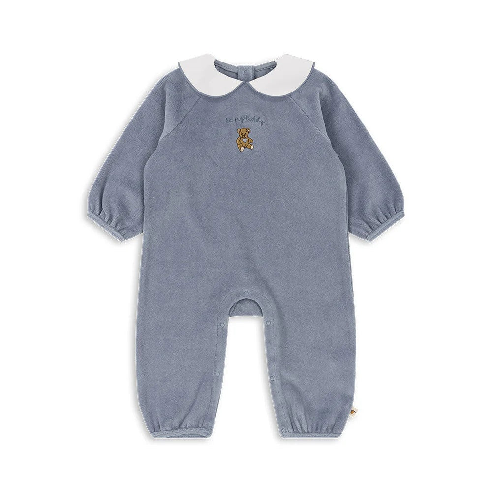 Konges Slojd Miffa Onesie Gots Trade Winds blue velour laid flat, white collar, teddy embroidery visible.