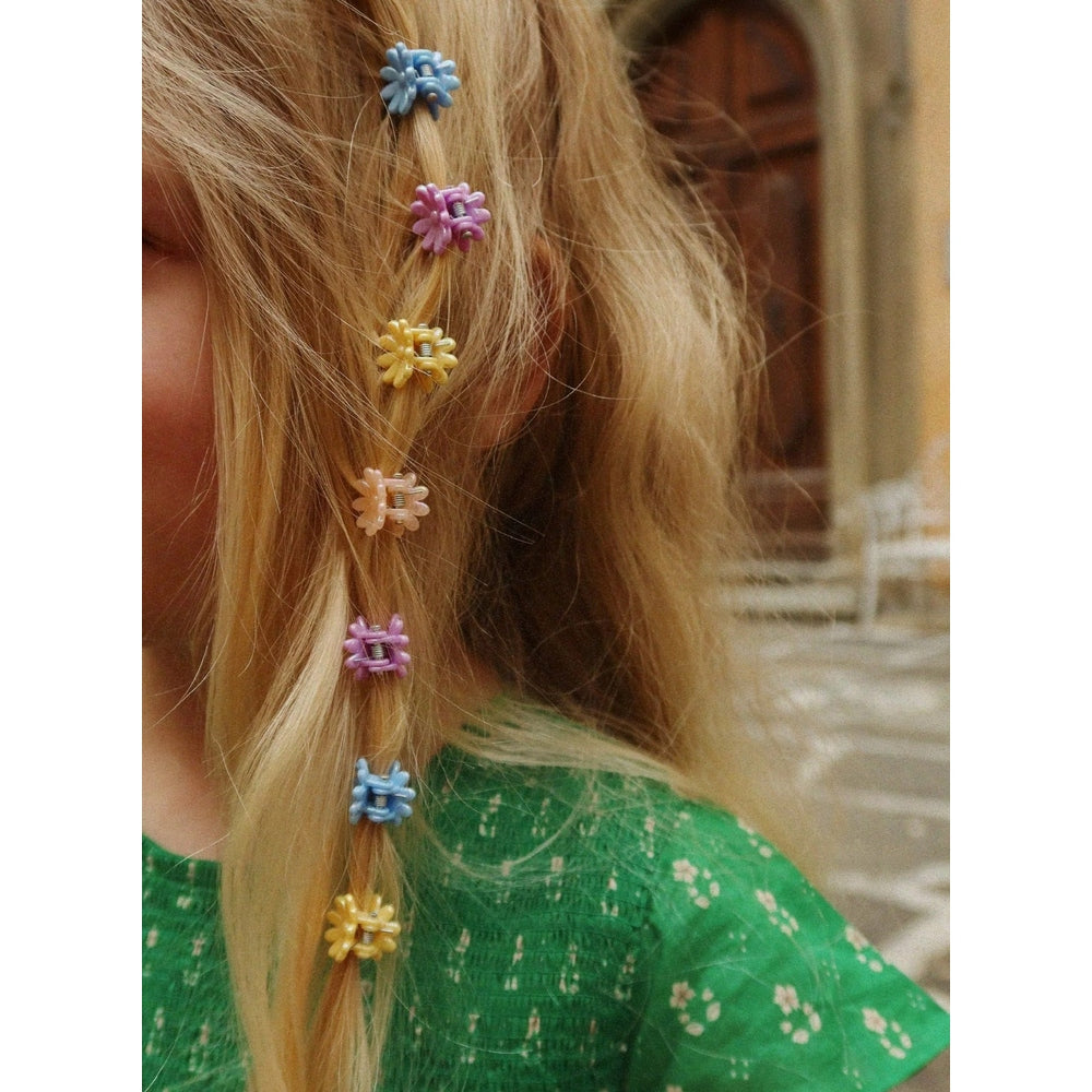 Konges Slojd Mini Flower Hair Claws in blue, purple, yellow, pink, and peach on a blonde strand.