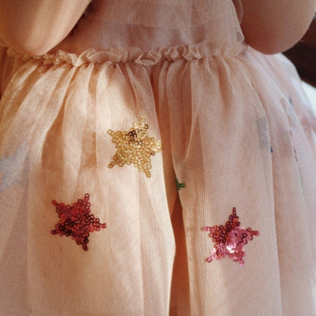 Konges Slojd Yvonne Fairy Dress Multi Star peach tulle worn by a child, sequined star patches in yellow and pink